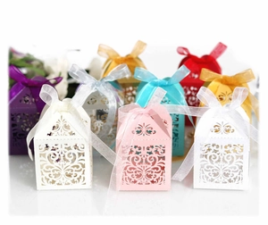 Laser-cut hollow gift boxes in various colors with elegant ribbon bows for weddings