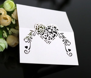 Detailed laser-cut heart pattern on white wedding place cards with elegant floral motifs