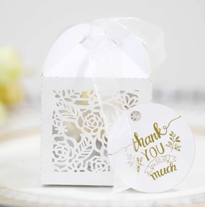 Detail of white laser-cut floral candy box with silk ribbon and gold thank you tag
