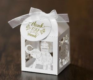 Detail of white laser-cut elephant candy box with elegant ribbon and thank you tag