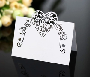 Macro detail of laser-cut white wedding place card with heart and scroll patterns