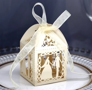 Detail of laser-cut ivory wedding favor box featuring bride and groom silhouette and ribbon