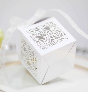Detailed macro view of laser-cut rose patterns on white square gift box with ribbon