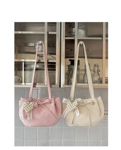 Detail of trendy shoulder bags with ruffled edges and pearl heart charms in pink and white