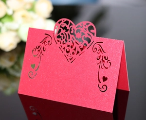Detail of red glitter wedding place card with intricate laser-cut heart floral pattern