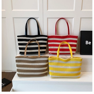 Cuatro bolsos tote trenzados a rayas de colores con asas de cuero en podio blanco