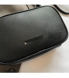 Close-up of black lychee grain leather crossbody bag with elegant gold logo detail