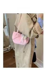 Pink bucket bag with lace bow and pearl charm detail shown on a model indoors