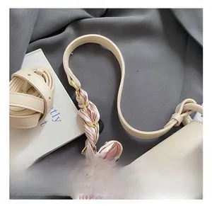 Detail view of cream leather square handbag with decorative silk scarf on handle