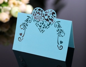 Detail of laser-cut heart and floral patterns on sky blue paper wedding table card