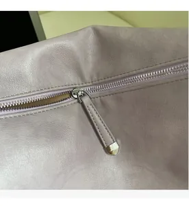 Detailed macro shot of the smooth metal zipper and purple leather stitching on the bag