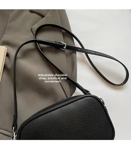 Detail showing the adjustable black litchi leather shoulder strap and silver buckle