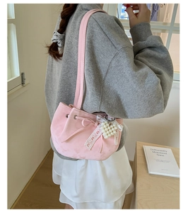 Pink drawstring bucket bag with lace bow and pearl heart pendant on shoulder