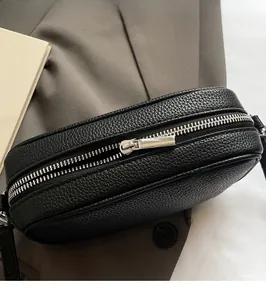 Close-up of premium silver metal zipper and hardware on black pebble leather handbag