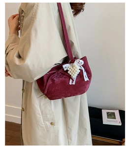 Detail view of burgundy velvet shoulder bag with bow, pearl charms and lace ribbon