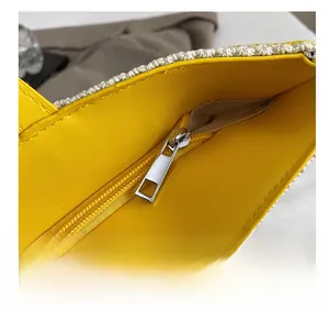 Detalle de la cremallera de metal y ribete de cuero amarillo en el bolso de lona