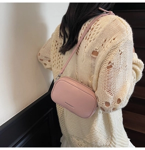 Détail d'un sac bandoulière en cuir grainé rose porté par un mannequin