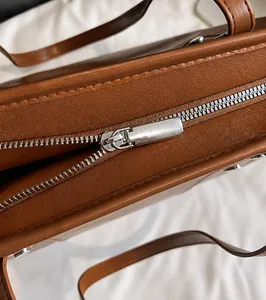 Close-up of silver metal zipper and smooth brown leather on large tote bag
