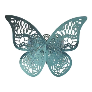 Macro detail of laser-cut butterfly napkin ring in metallic teal blue with hollow lace pattern