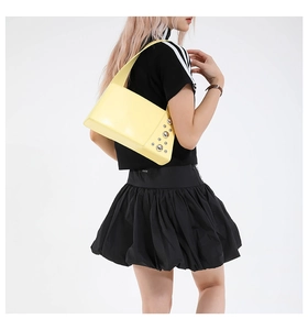 Detail view of yellow leather shoulder bag with punk rivets and sleek side profile
