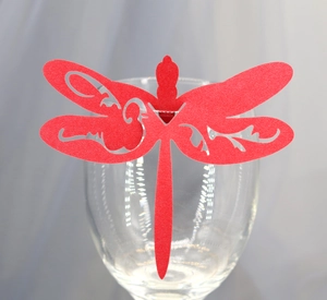 Macro detail of laser-cut red glitter paper dragonfly card for wedding glass decor