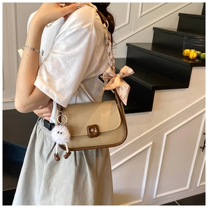 Detail of two-tone crossbody bag with striped silk scarf ribbon and plush charm
