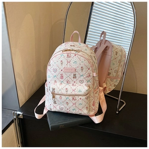 Detail showing cartoon bear print texture and pink leather brand tag on backpack