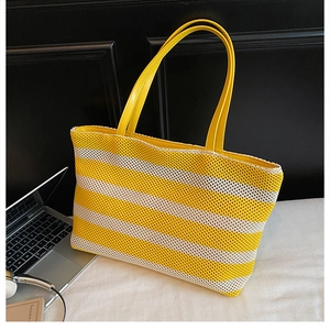 Detalle del bolso tote tejido a rayas amarillas y beige con asas de piel premium