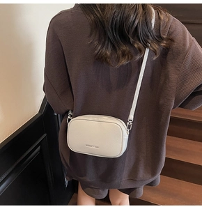 Vue détaillée du petit sac à bandoulière en cuir grainé blanc porté par un mannequin