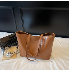 Detailopname van de bruine PU-leren shopper met zilveren klinknagels en modetekst
