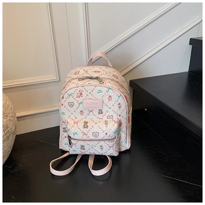 Detail of cute cartoon bear print and pink leather logo on a beige mini backpack
