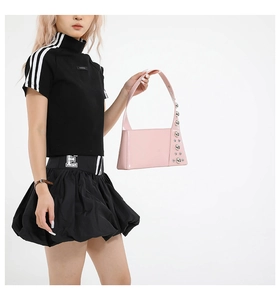 Detail of pink patent leather bag featuring silver metal rivets on the side and shoulder strap