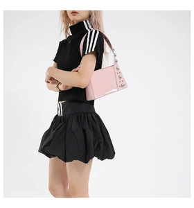 Pink patent leather underarm bag with decorative metal rivets shown on a fashion model