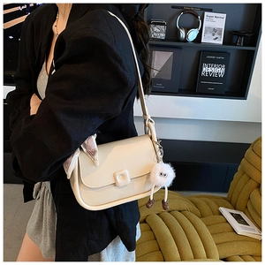 Detail view of cream shoulder bag with silk scarf and cute white plush doll charm