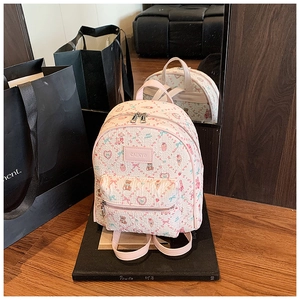 Detail of pink teddy bear print mini backpack featuring a gold-tone brand logo plate
