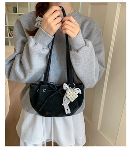 Detail of black velvet shoulder bag with drawstring bow and heart pearl charm