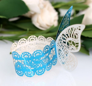 Detail of laser-cut lace cupcake wrapper with blue butterfly design for wedding decor