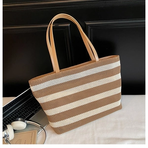 Vista detallada del bolso tote tejido a rayas con asas de cuero estilo lifestyle