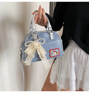 Détail du sac à main en jean avec nœud en dentelle, perles et écusson de chien
