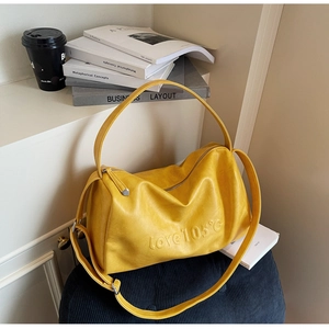 Detail of yellow leather tote featuring love 105 embossed lettering and zipper closure
