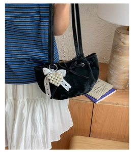 Detailed close-up of a black velvet tote bag with pearl heart charm and lace bow details