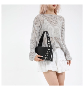 Detail of black glossy leather underarm bag featuring large silver metal rivets on the strap