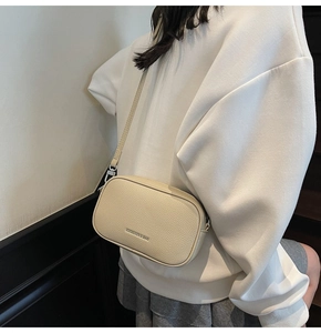 Détail du sac bandoulière en cuir grainé beige avec boucles métalliques argentées