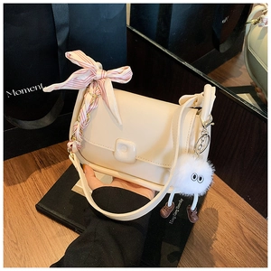 Detail of cream PU leather crossbody bag with silk scarf bow and plush charm