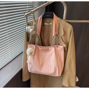 Dettaglio della borsa tote rosa pieghettata con catena in metallo e pompon bianco