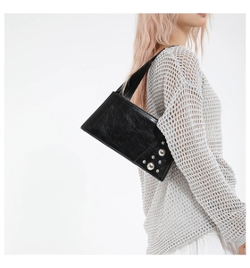 Detail of black patent leather underarm bag featuring silver metal rivet embellishments