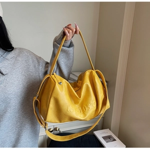Detail of soft yellow leather tote featuring embossed LOVE 105C lettering and texture