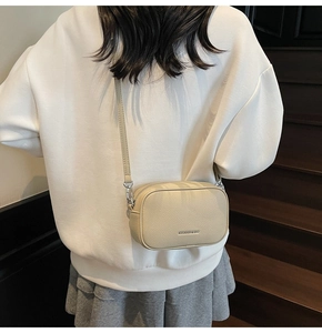 Detail of off-white lychee leather crossbody bag with logo and metal zipper closure