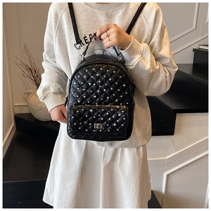 Dettaglio dello zaino trapuntato nero con strass su modella in un ambiente minimalista