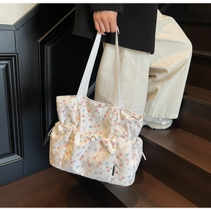 Detailed view of canvas tote bag with floral patterns and functional front pockets